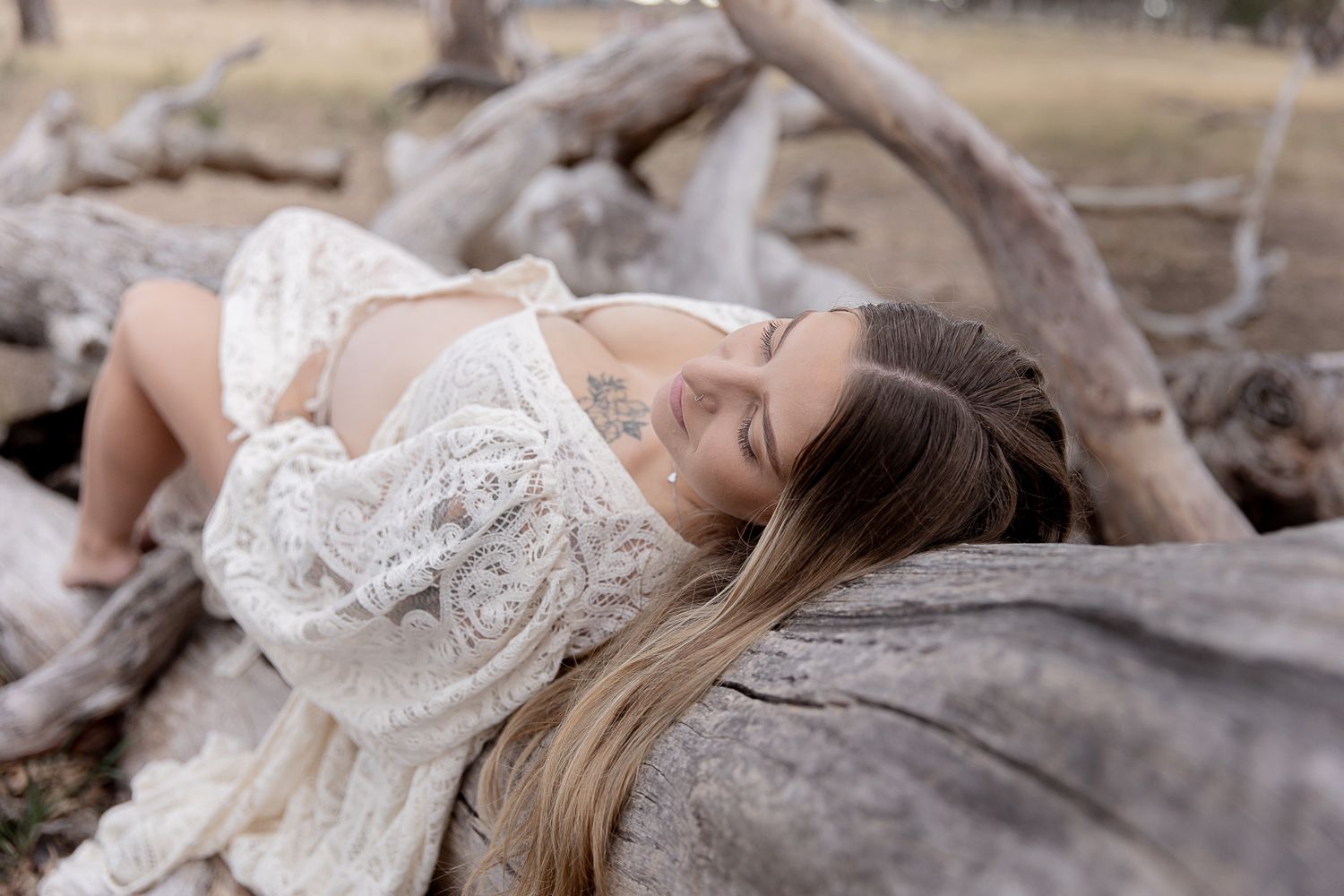 Mother to be laying on a log during a professional maternity photo shoot.