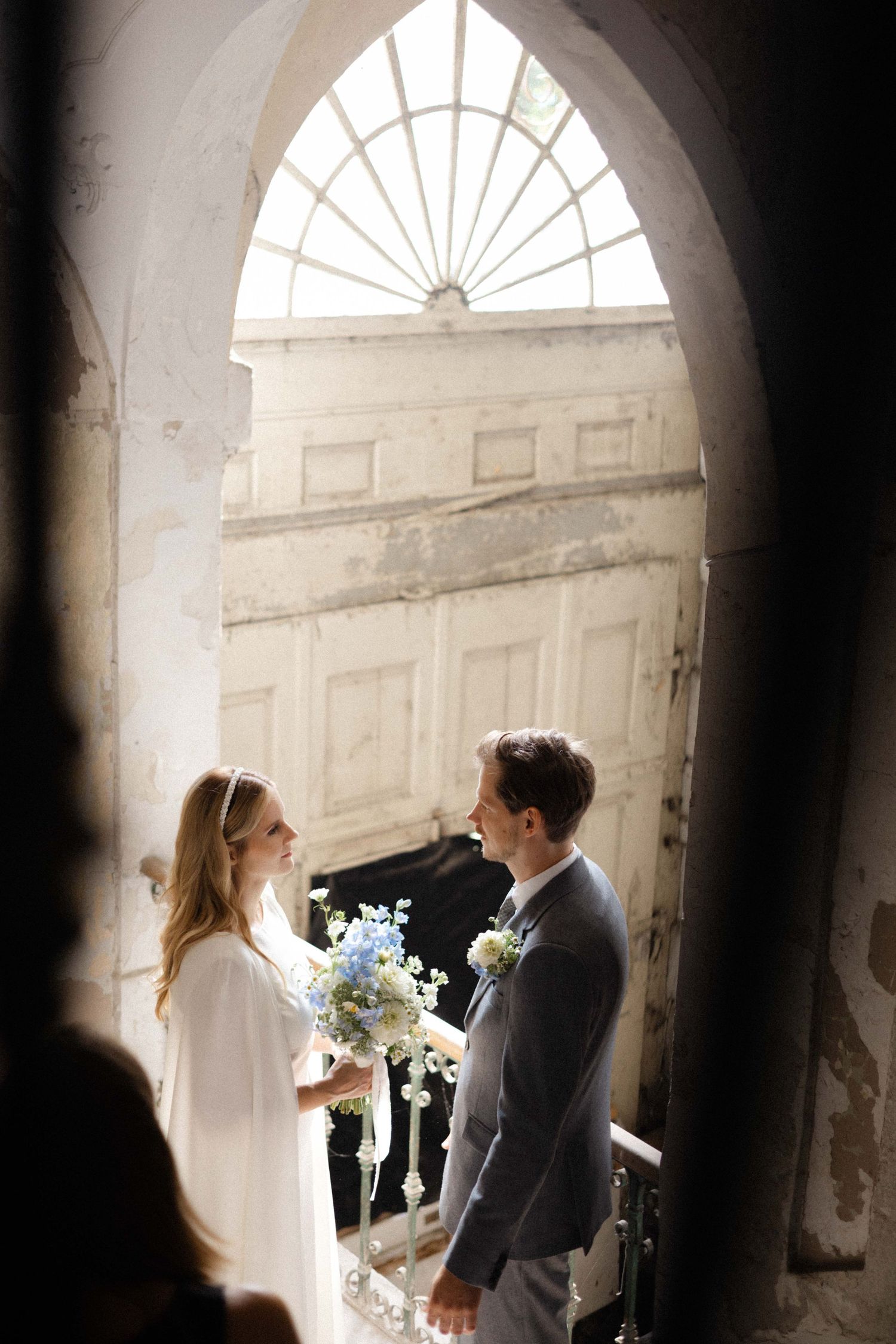 Bride and groom walking up stone stairs in historic building, motion blur capturing wedding day excitement.