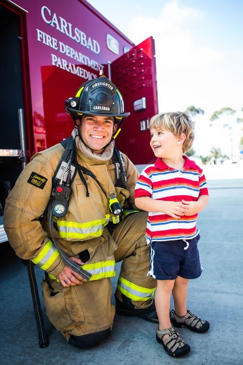 A Carlsbad firefighter and young child share a moment in front of a fire truck.