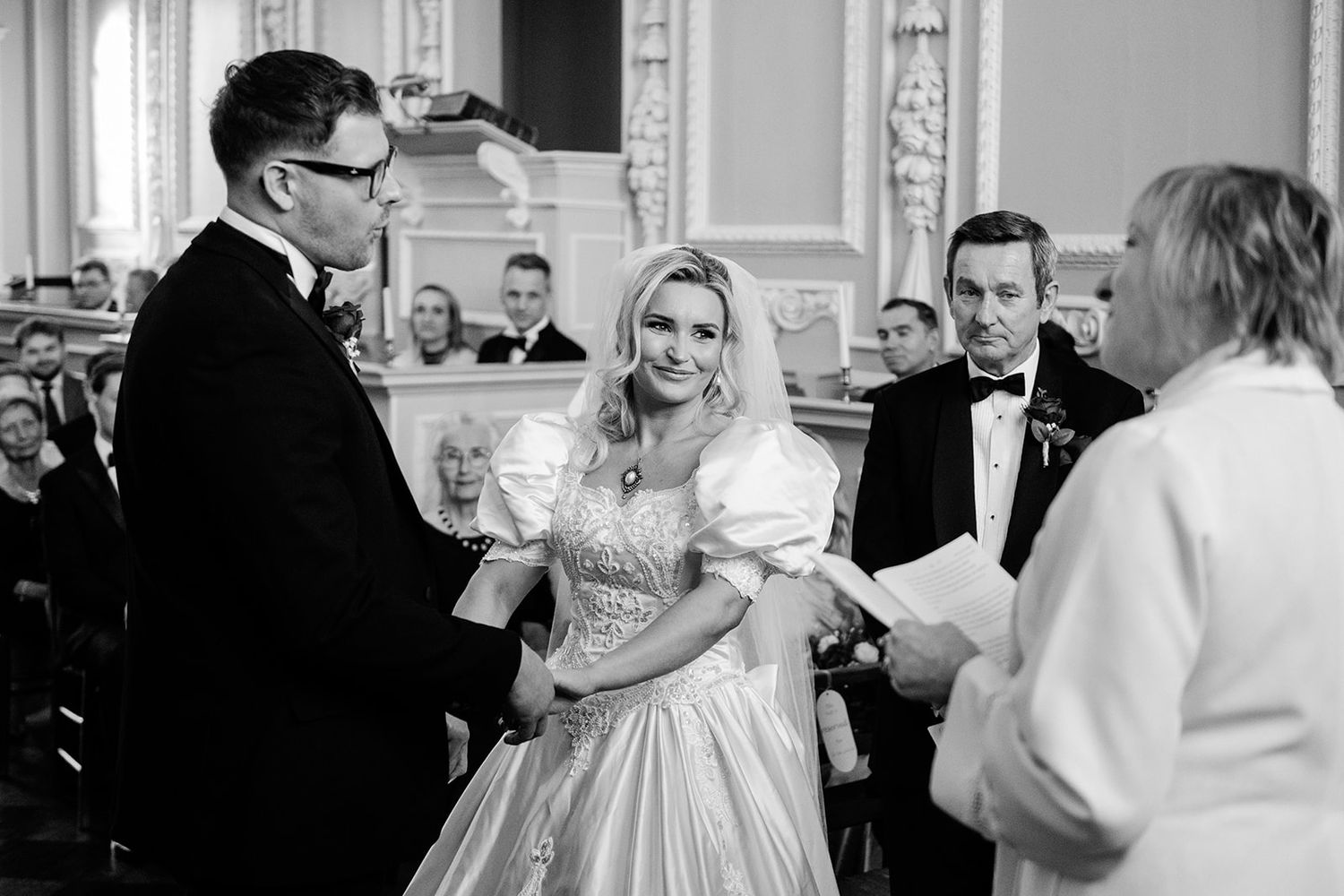 Bride and groom exchanging vows at elegant black and white wedding ceremony indoors.