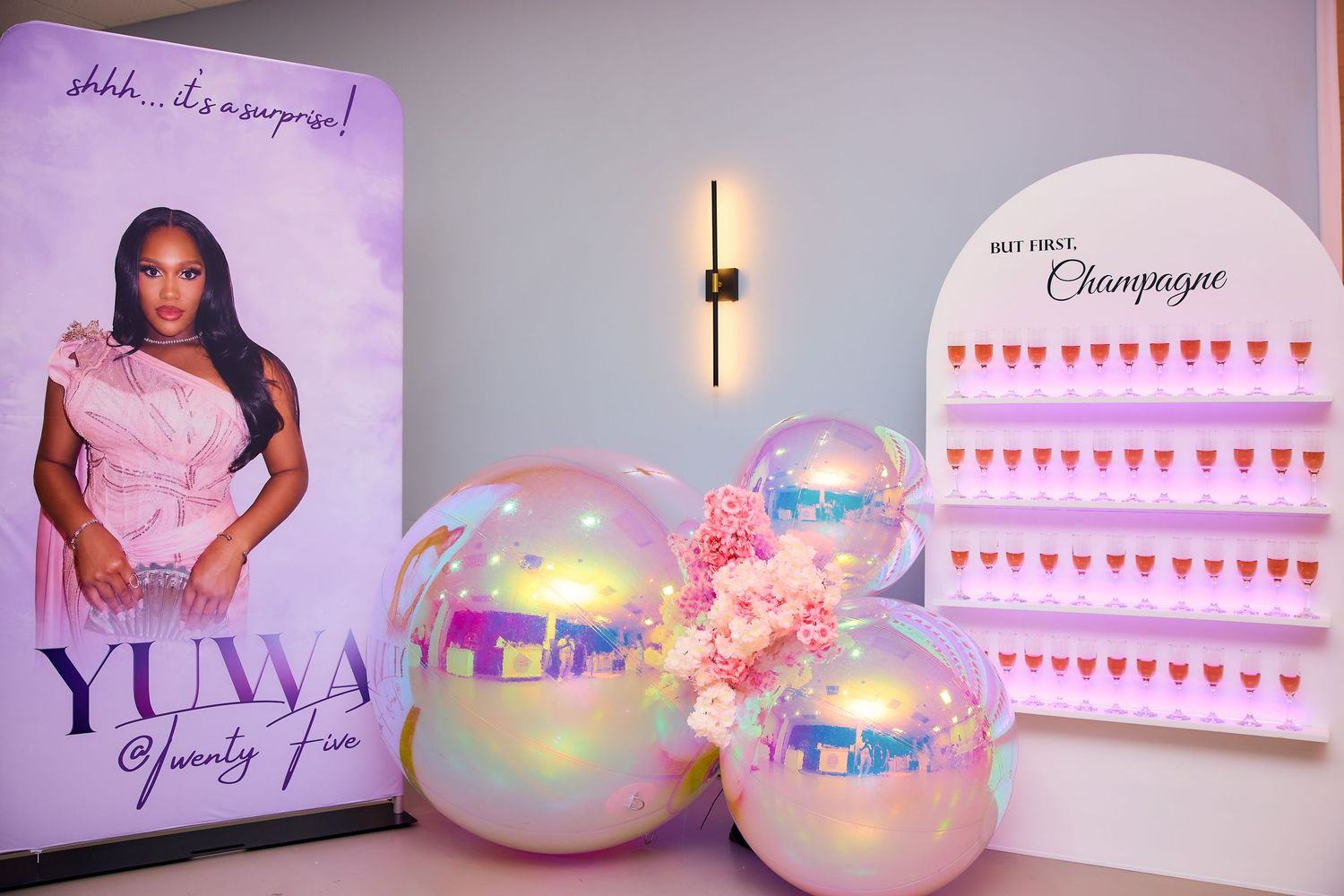 Elegant birthday party setup with iridescent balloons, floral decor, and a personalized banner reading Yuwa at a surprise celebration.