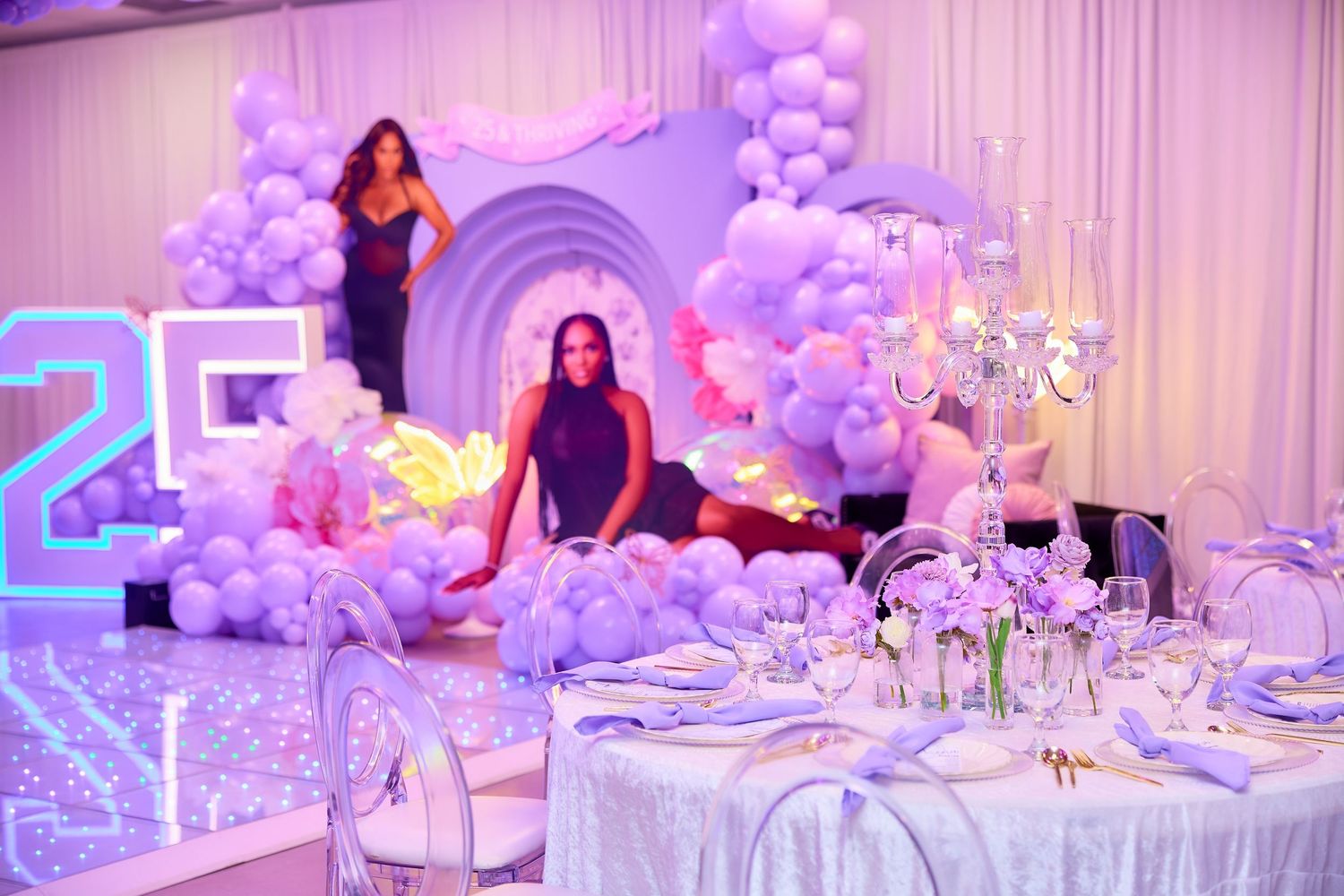 Elegant purple balloon arch display with large photos and glowing 25 number decoration.