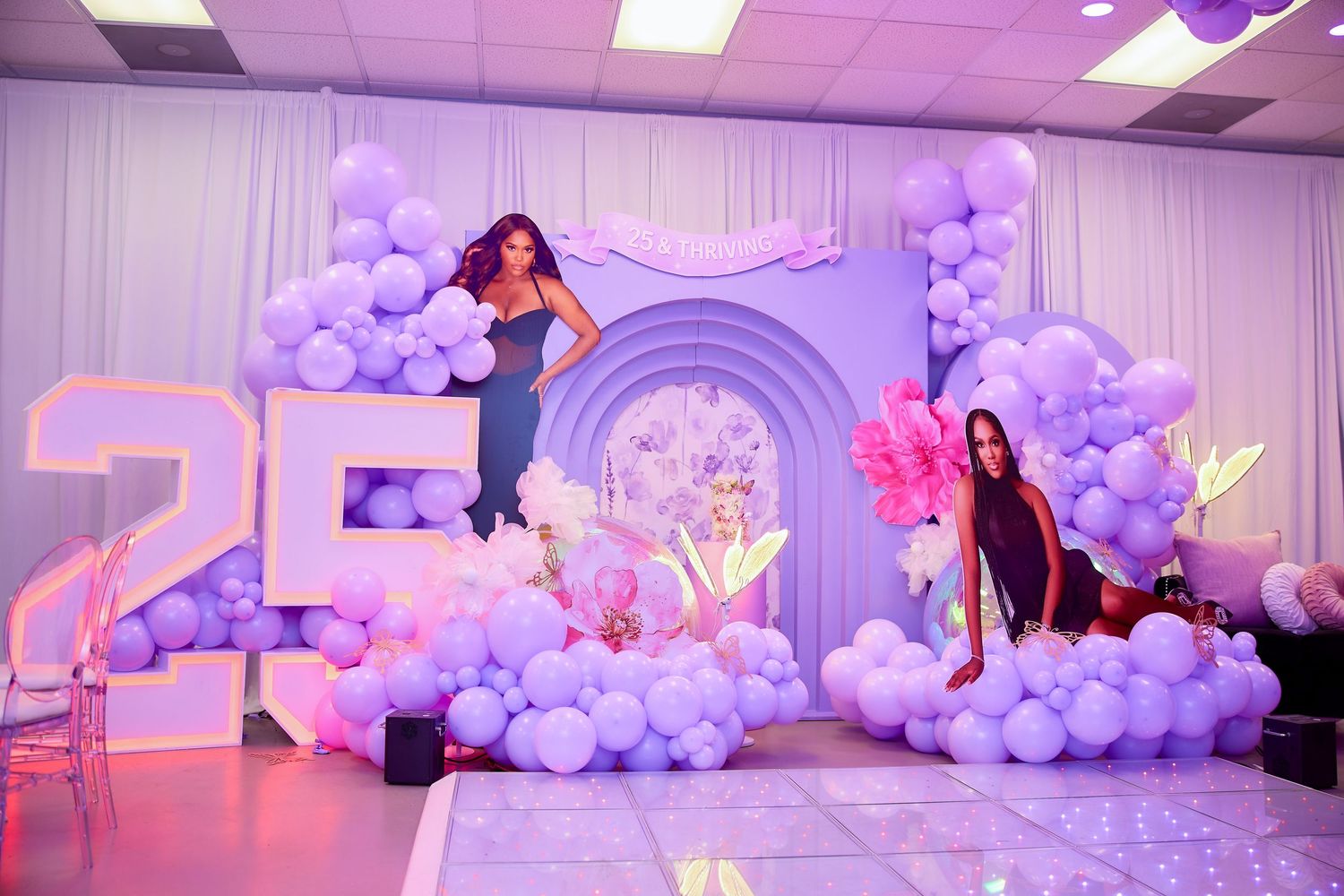 Elegant 25th birthday party setup with purple balloon arch, large number display, and life-size cutout.