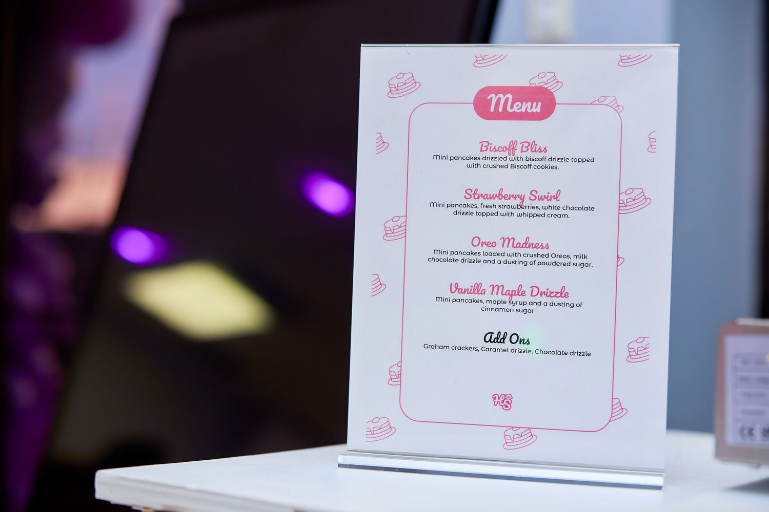 Elegant pink and white party menu sign displayed on white table at birthday event.