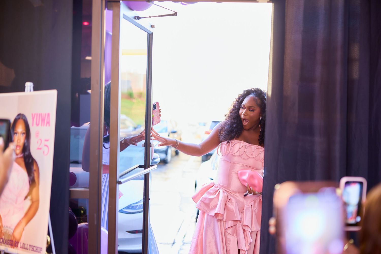 Woman in pink ball gown opening doors at a birthday celebration event.