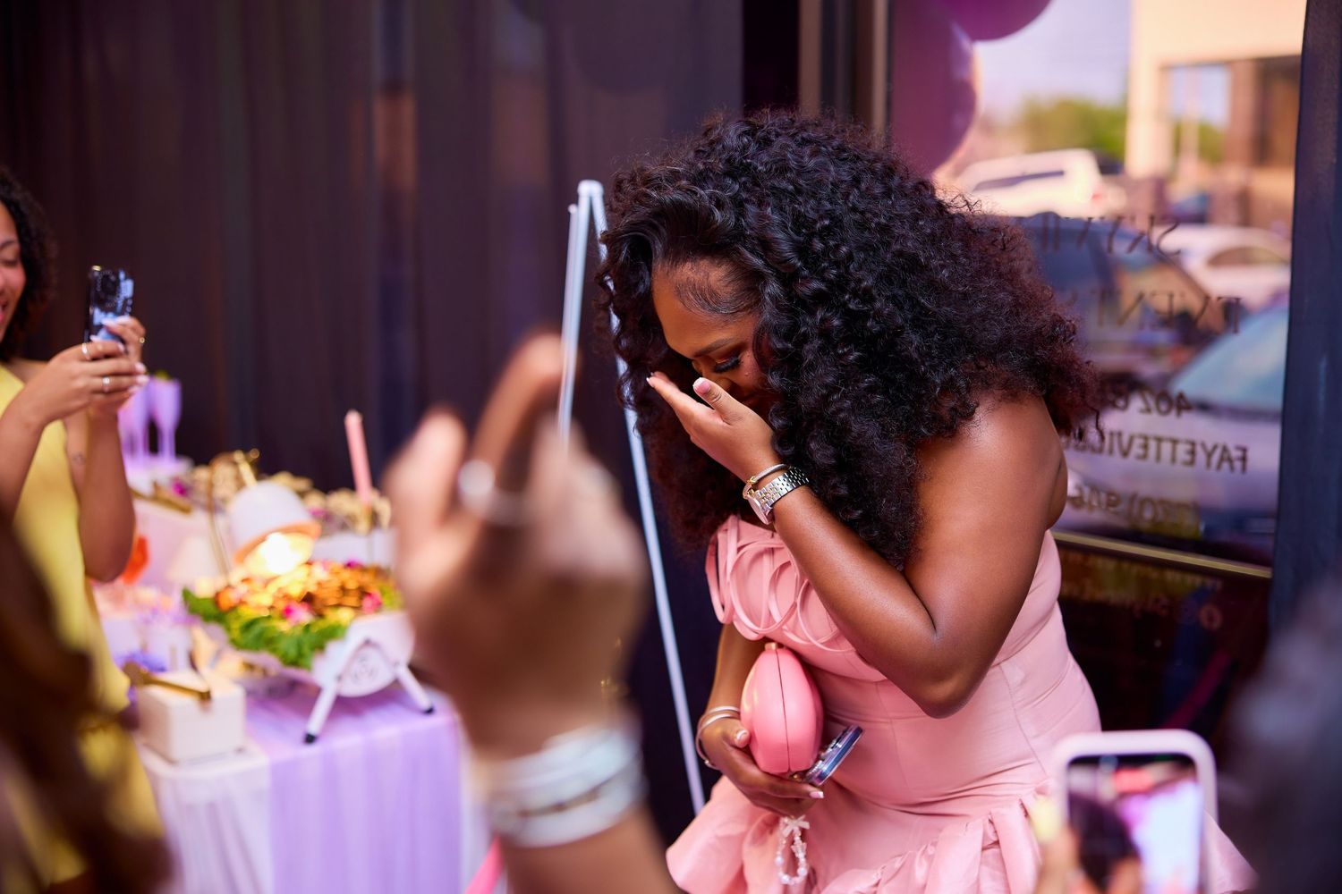 Woman in pink dress emotional and overwhelmed with joy at a festive celebration event.