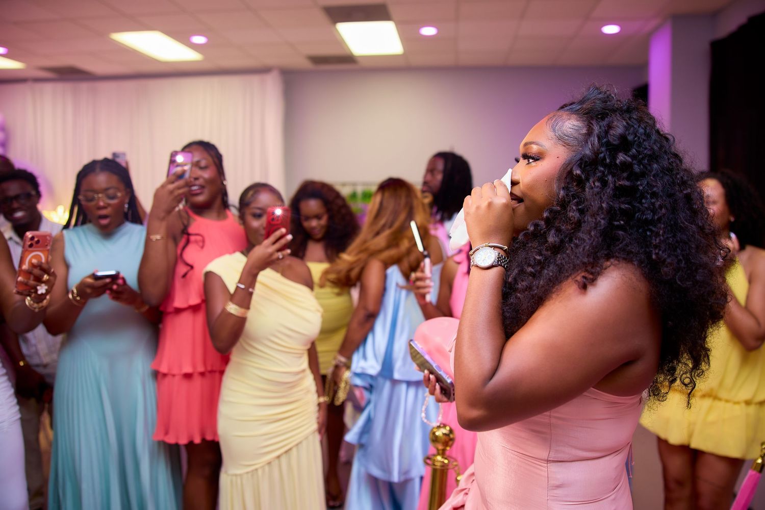 Birthday girl singing into microphone surrounded by guests at colorful celebration party.