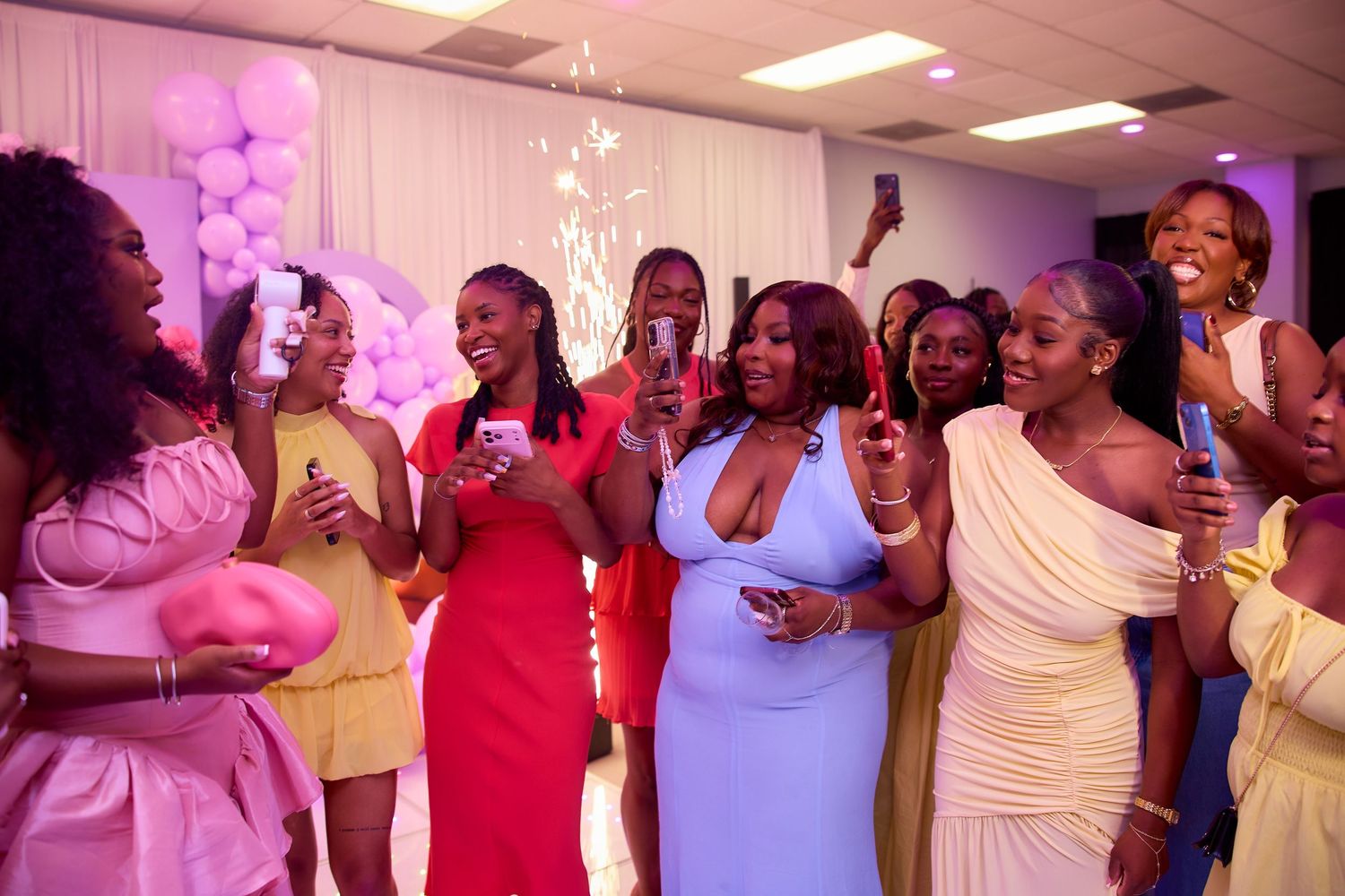 Group of women celebrating and taking photos at a colorful birthday party event.