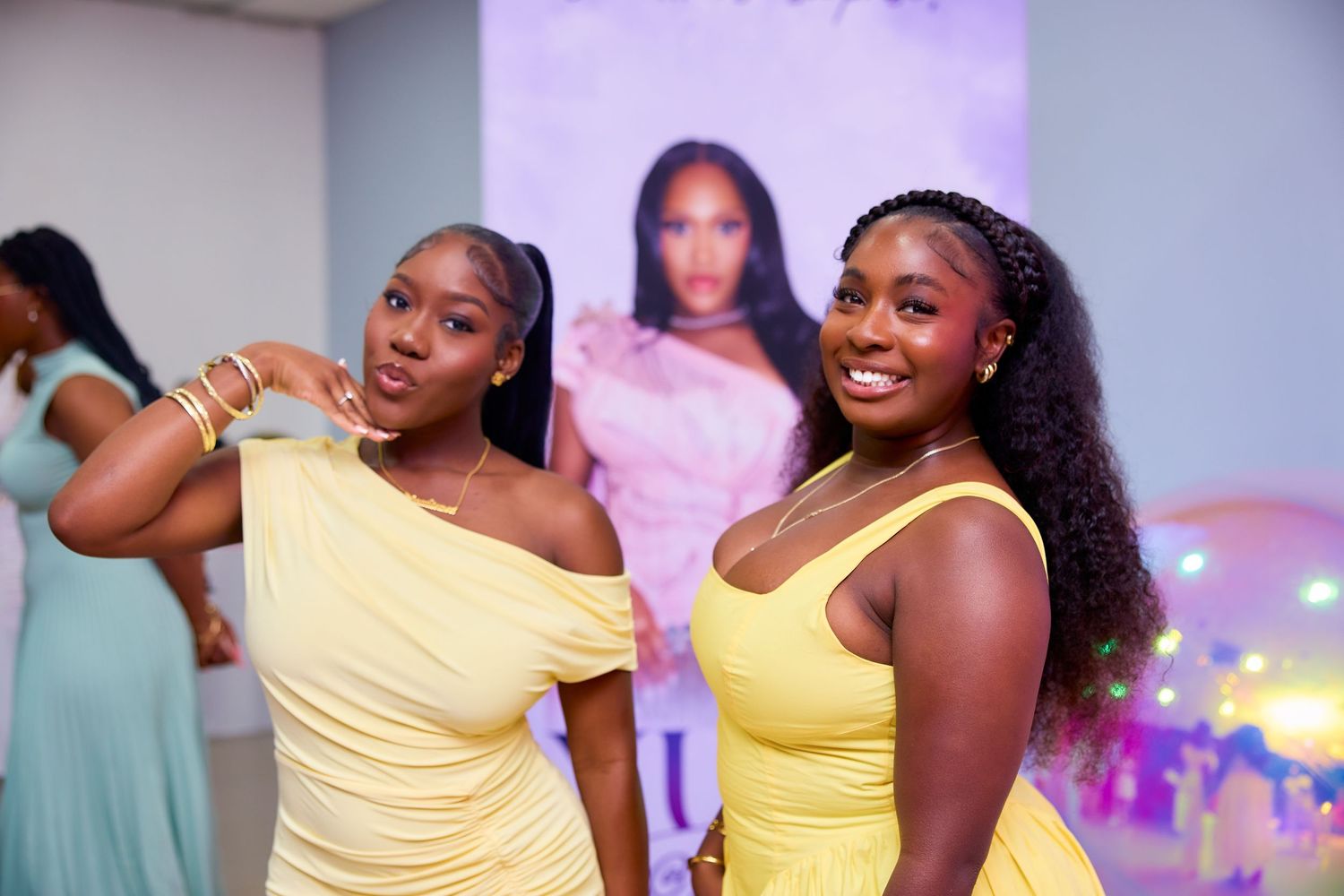 Two women in matching yellow dresses smiling at elegant birthday celebration.