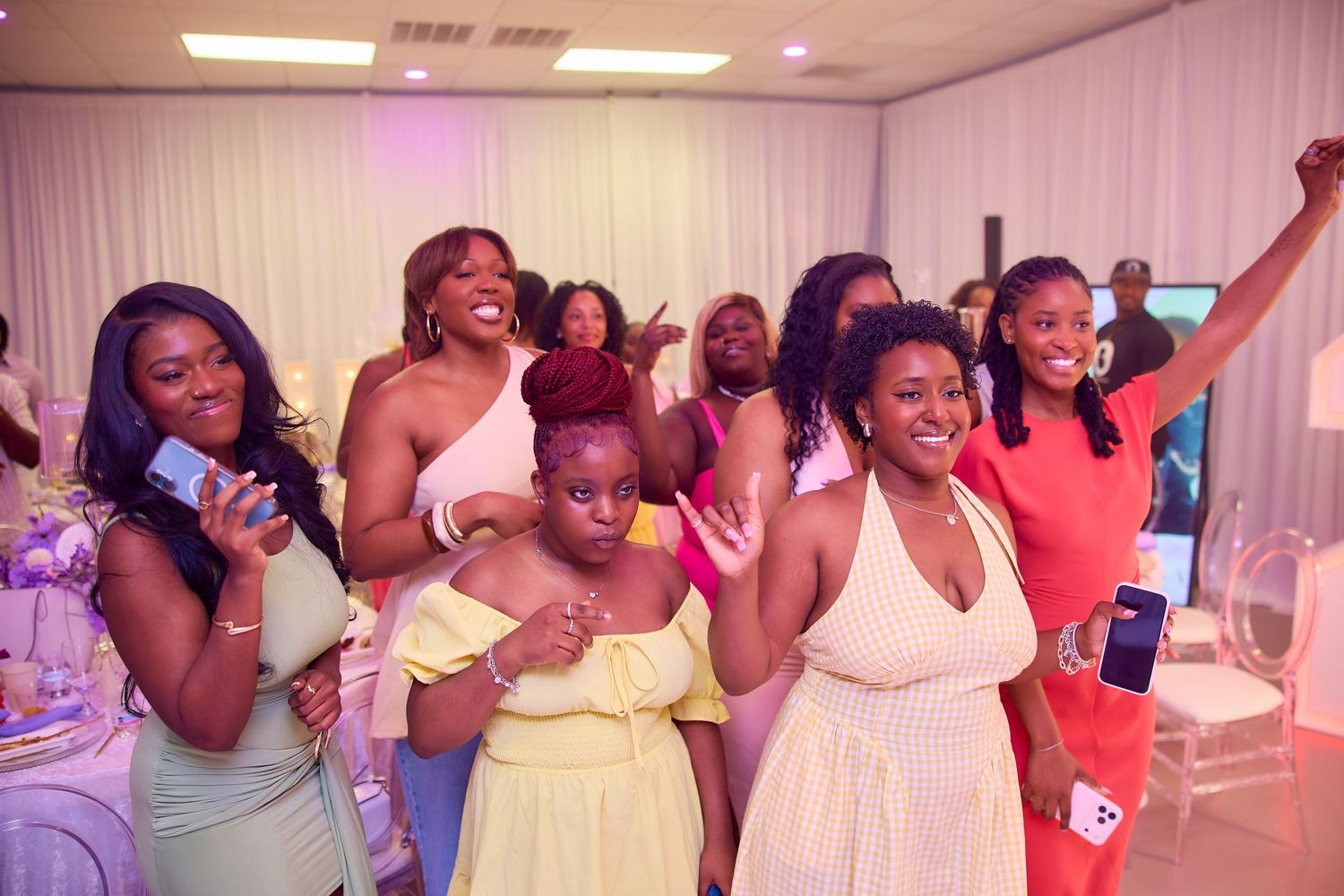 Group of joyful women in colorful dresses celebrating at a party event.