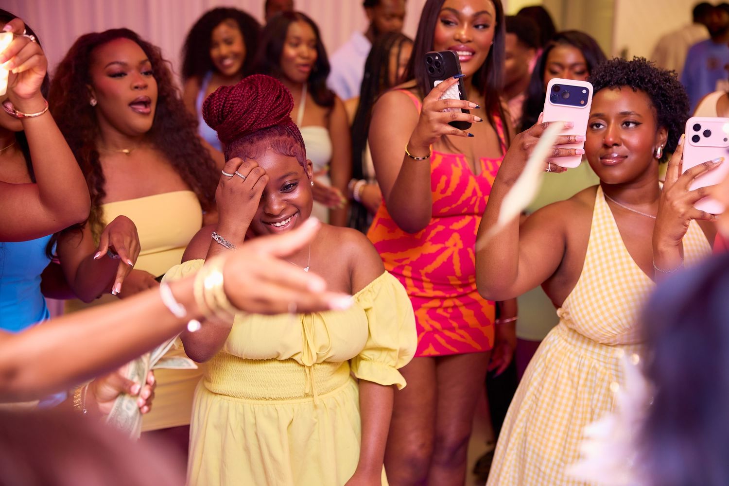 Guests dancing and celebrating at a colorful birthday party with phones raised.
