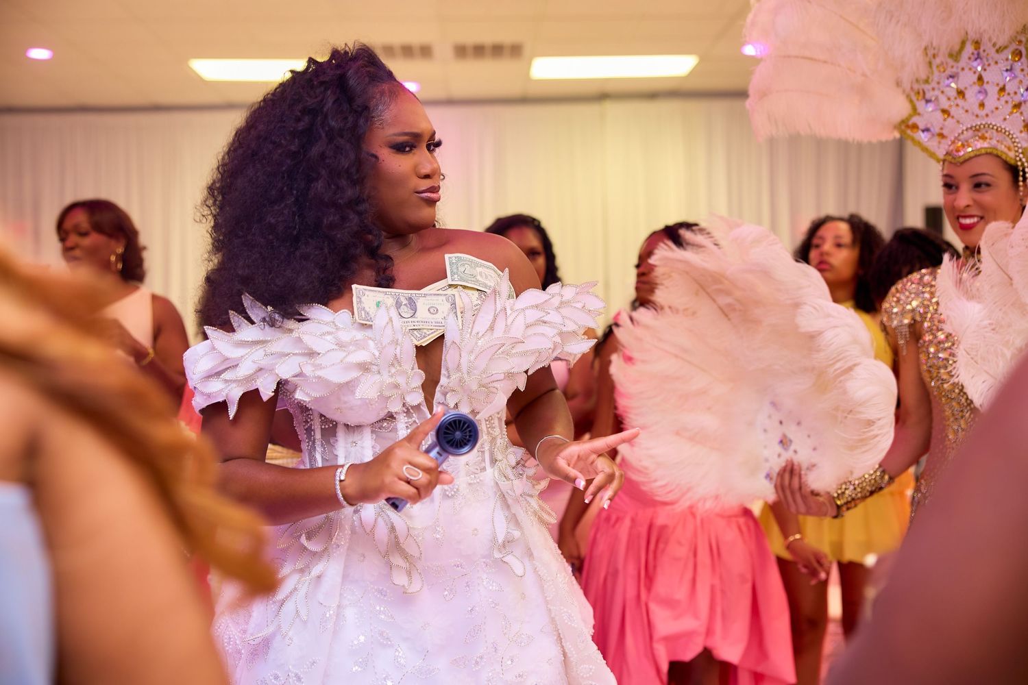 Woman in white feathered dress with dollar bills dancing at a celebration party.