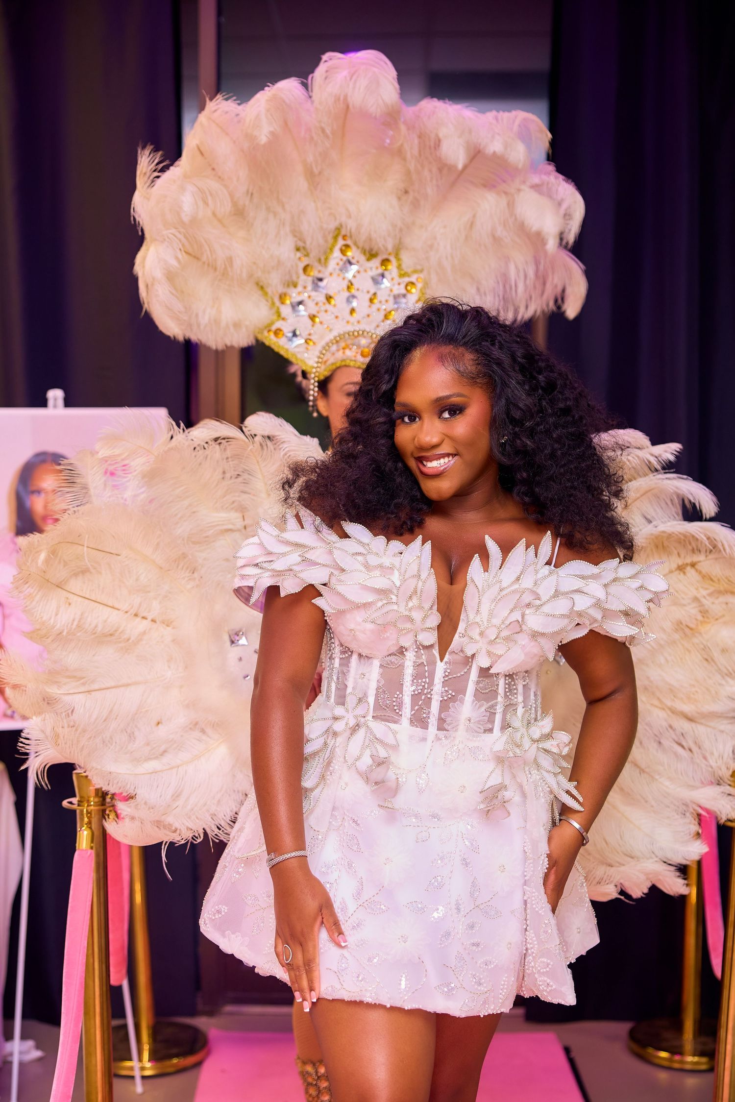 Woman in white feathered costume with large feather wings at a glamorous event.