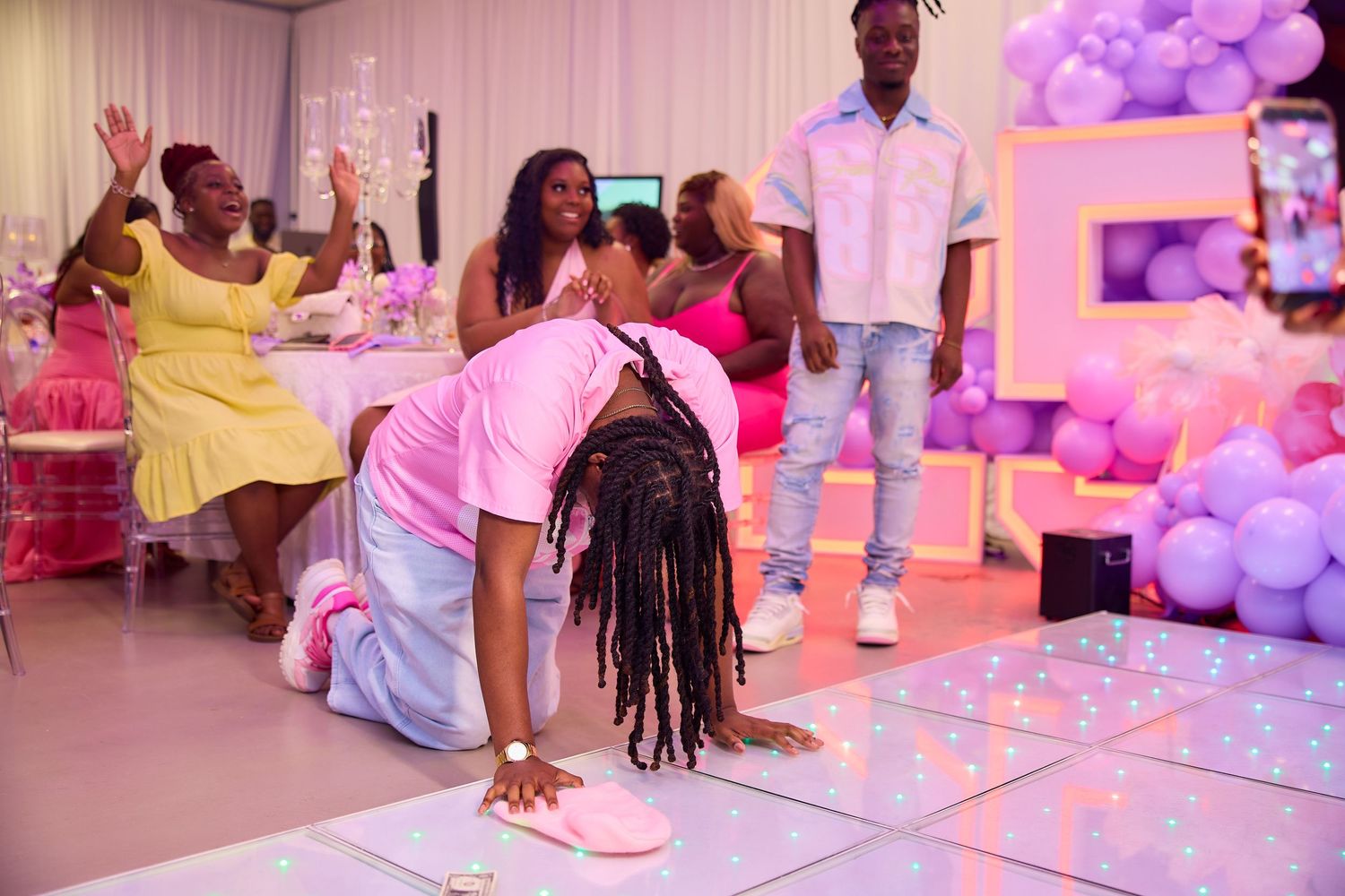 Guest does the worm on light-up dance floor at colorful purple and pink birthday party.