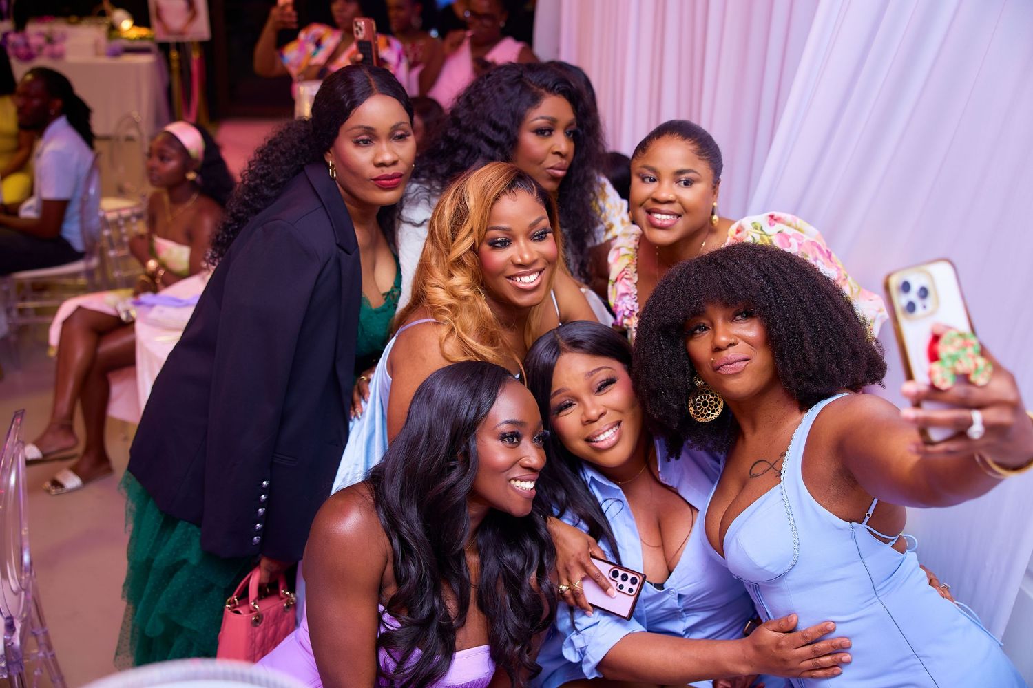Group of women posing for selfie at pink and white decorated birthday celebration.