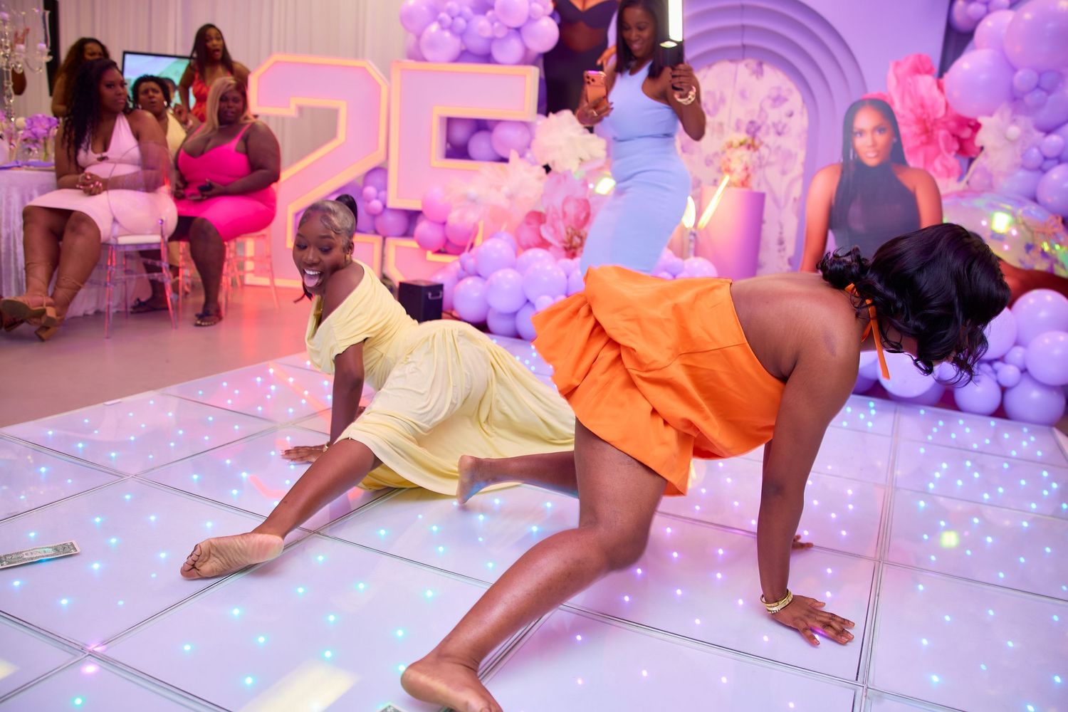 Two women dancing energetically on a white LED dance floor at a birthday party.