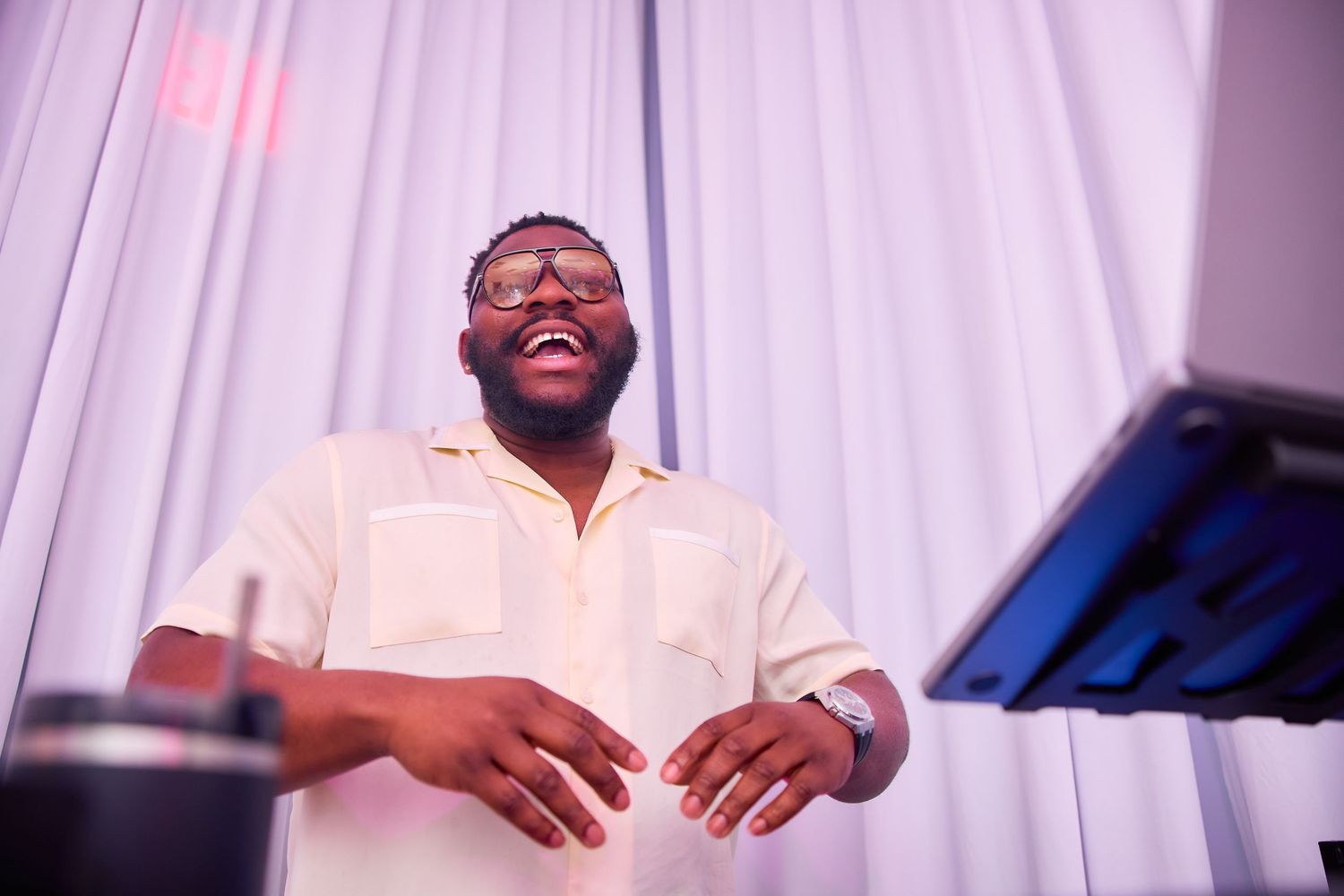 A joyful Black man laughing and gesturing at a keyboard during a live music performance at an elegant event.