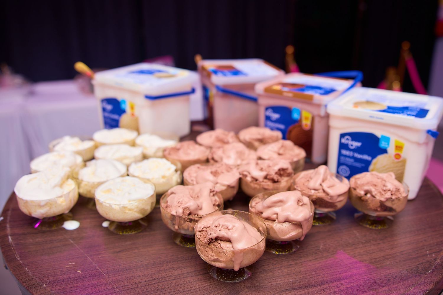 Assorted chocolate and vanilla ice cream cups displayed on a table with large Breyers ice cream containers at an event.