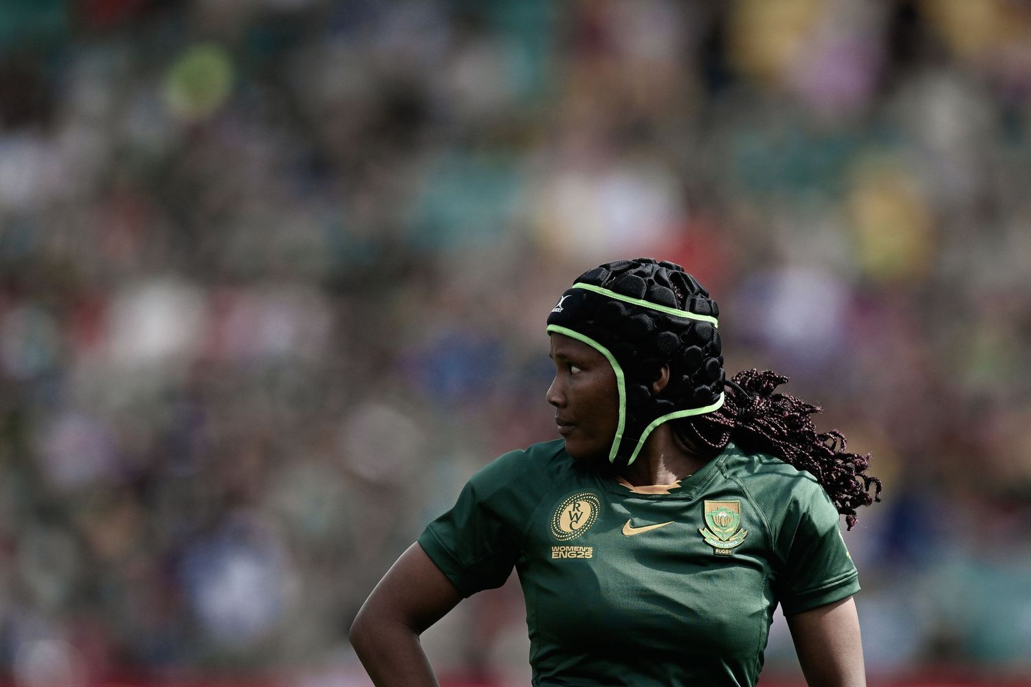 Rugby player in dark green South African Springboks uniform and protective headgear stands on field during match.
