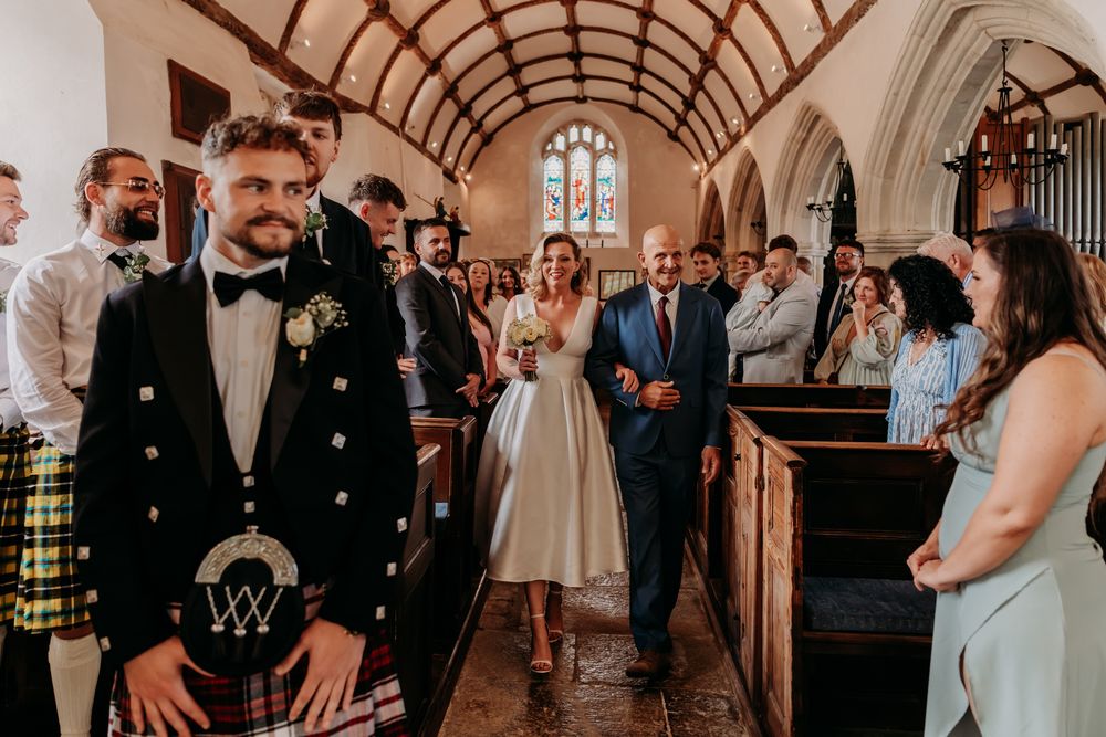 Guests celebrate on a dance floor under arched ceilings at an indoor wedding venue during an evening reception.