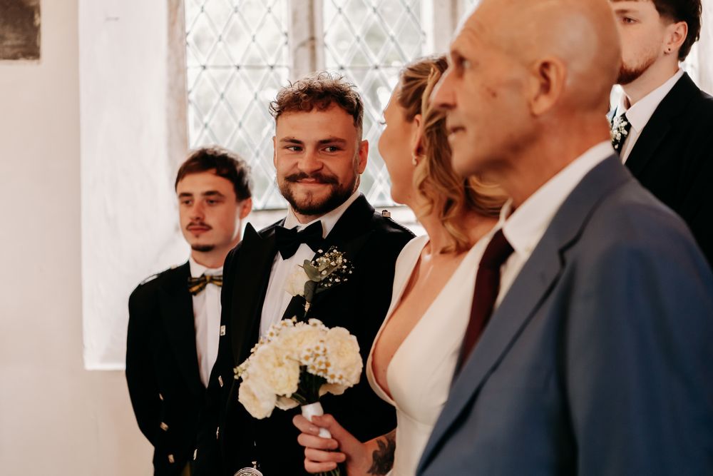A couple shares an emotional first kiss during their wedding ceremony while guests look on in a chapel.