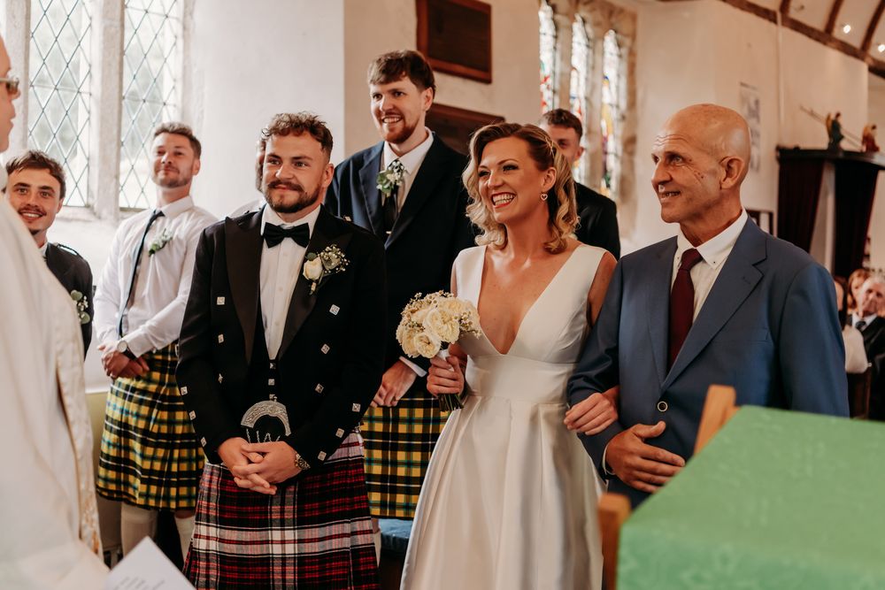 A wedding celebration at a church featuring guests wearing traditional Scottish kilts and formal attire.