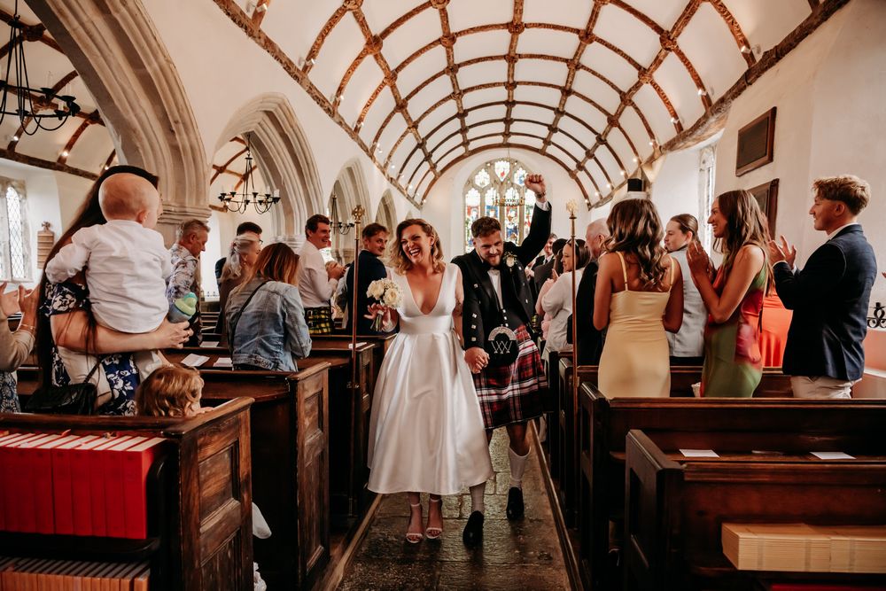 Wedding guests gather under an elegant arched ceiling in a vintage-style reception venue during a celebration.