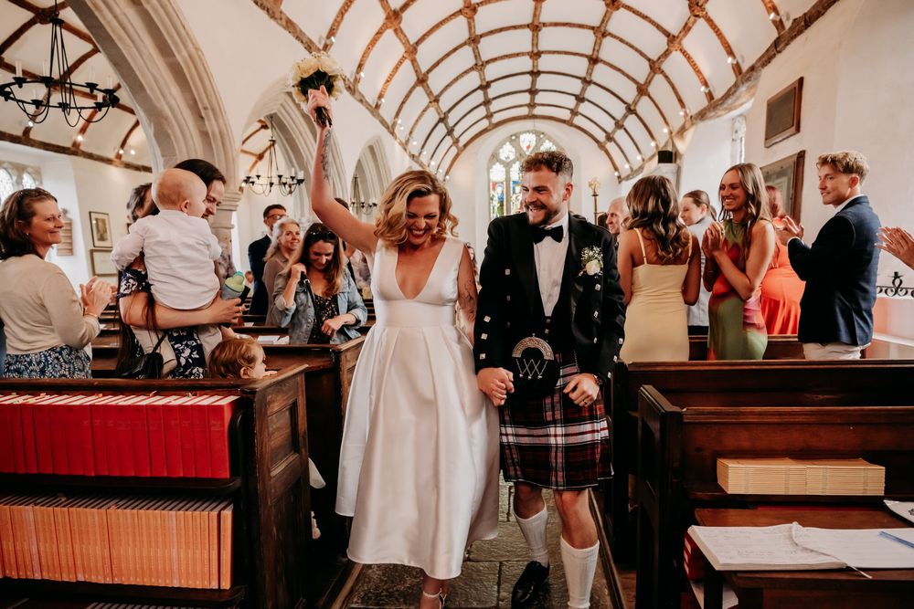 A joyful wedding celebration inside a historic church with vaulted ceilings and wooden pews.