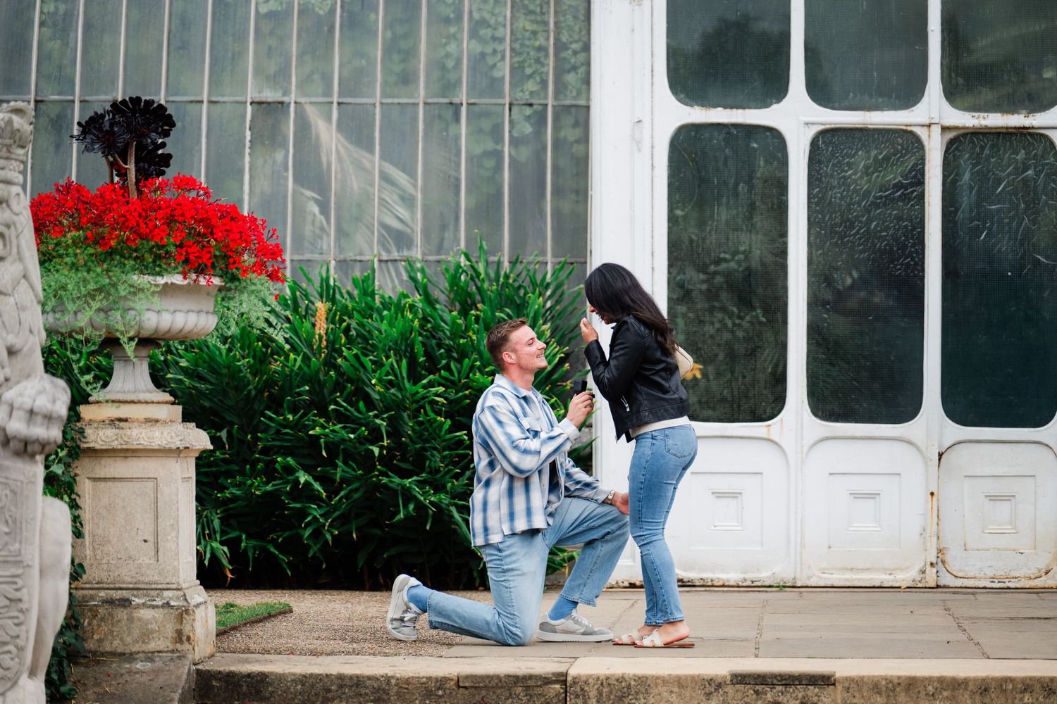 Students relax and study on steps outside a building with white columns and glass windows.