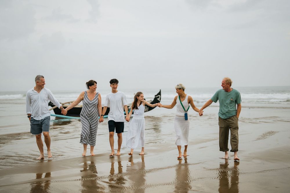 Group holding hands while walking together on a misty beach shoreline.