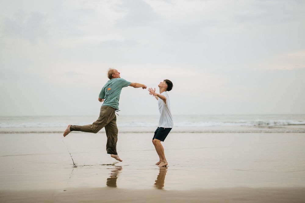 Two people dancing and playing together on wet sand at the beach.
