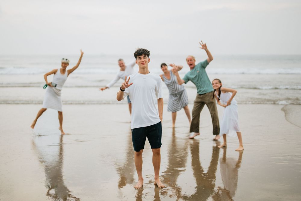 Group striking fun poses on the beach with waves in the background.