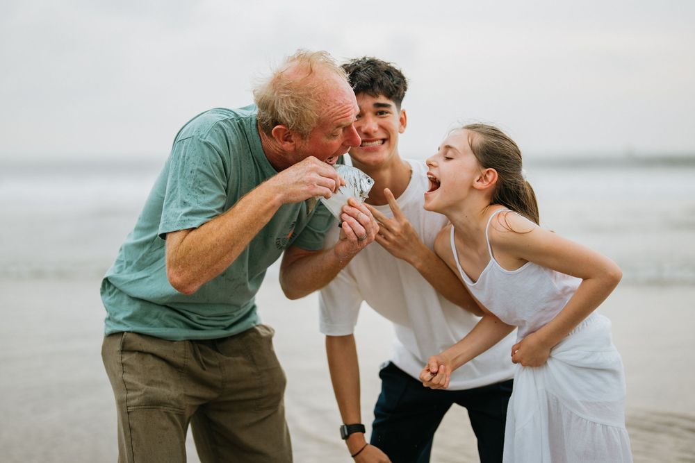 Family shares playful moments together on a cloudy beach during a photo session.