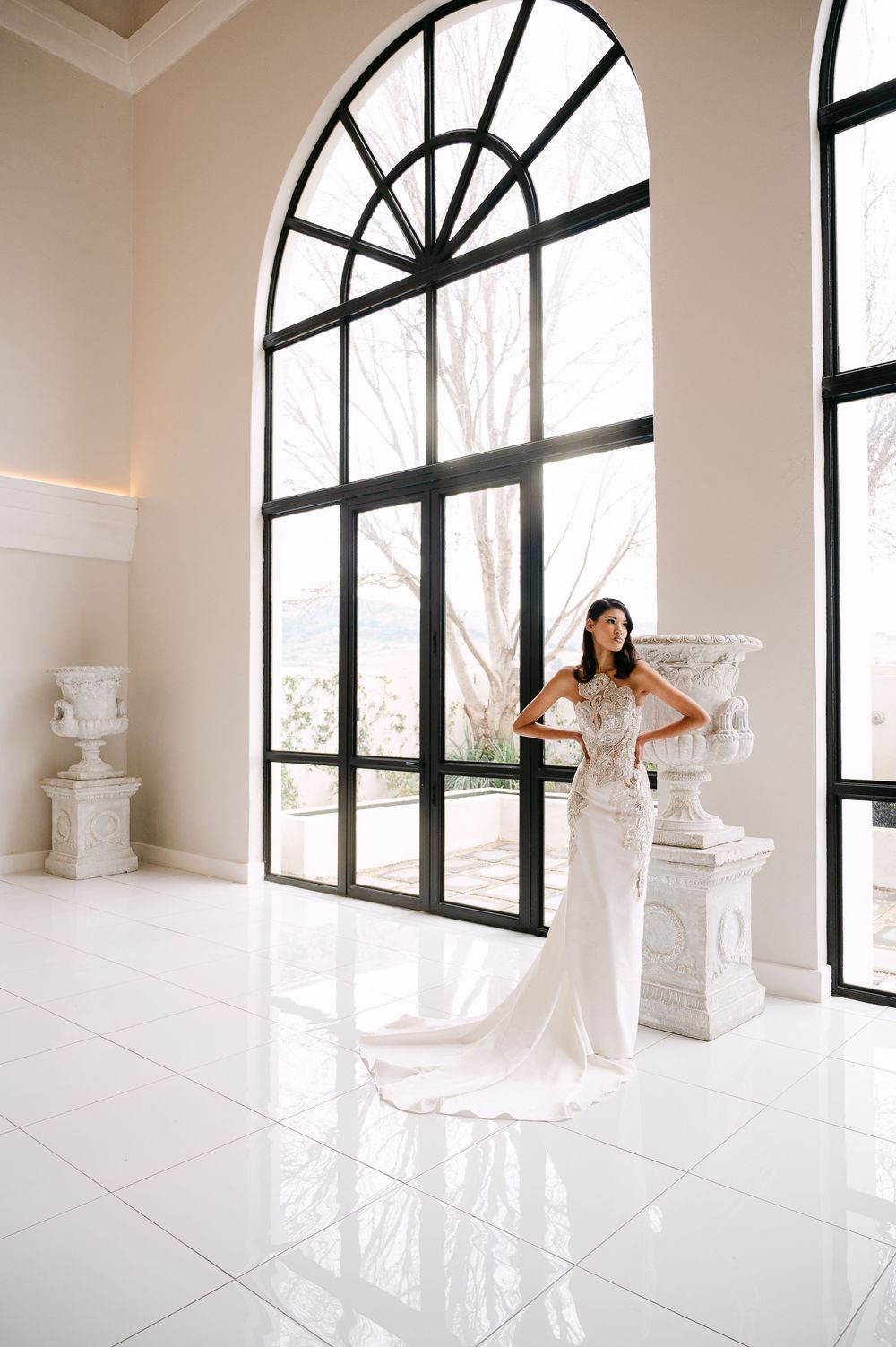 Modern bridal editorial in minimalist white space featuring dramatic black-framed windows.