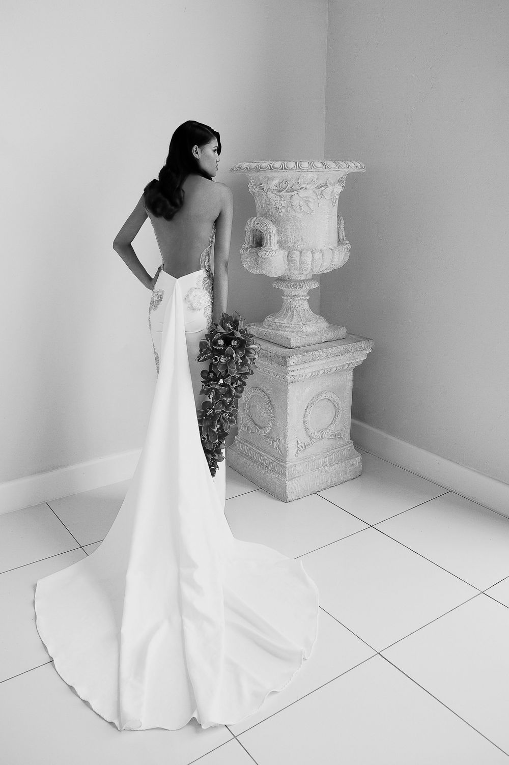 A black and white photo series showing the elegant flow and movement of a white wedding gown against a minimalist backdrop.