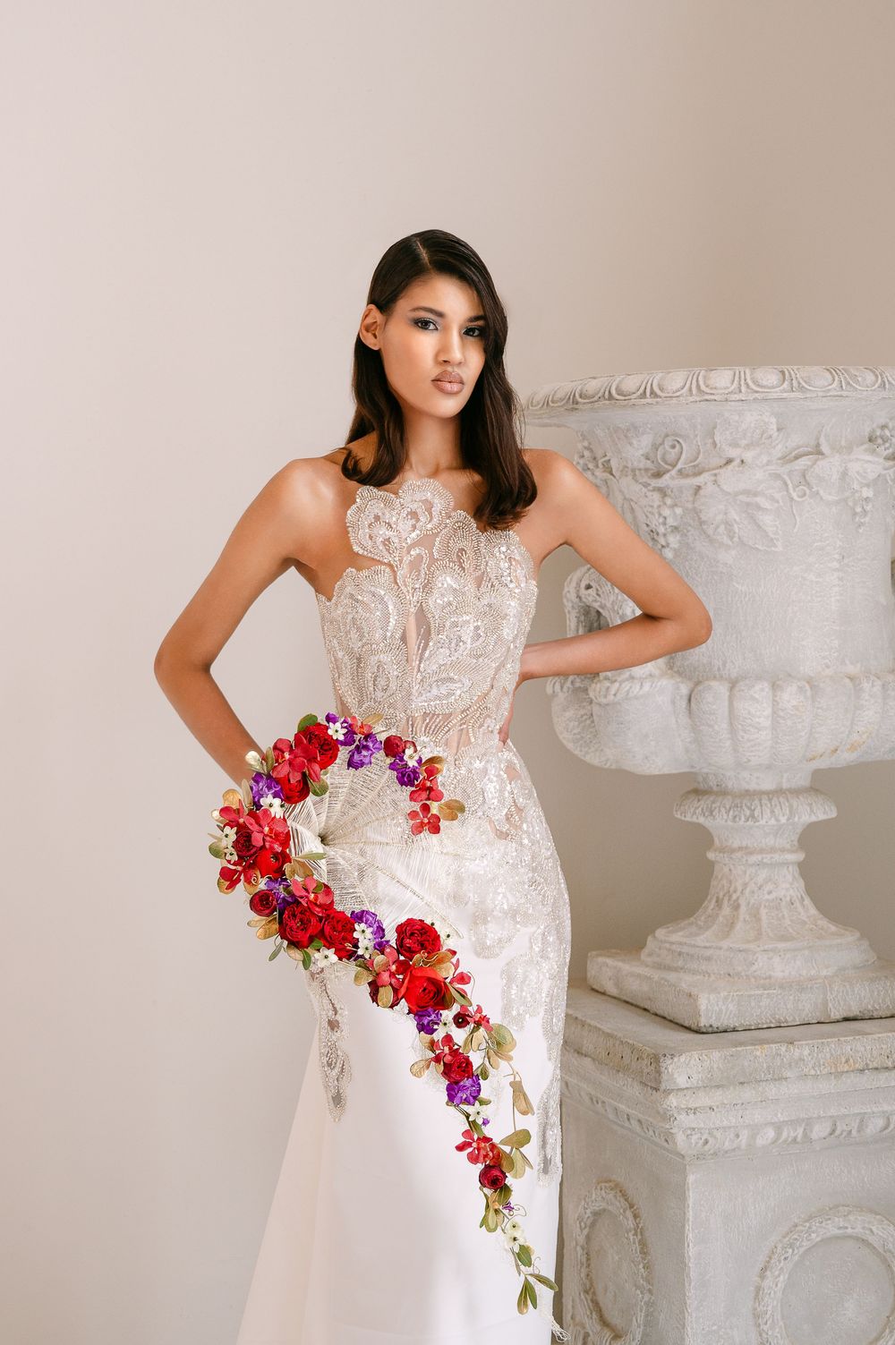 Wedding fashion photo showing detailed lace bodice gown with colorful trailing floral bouquet.