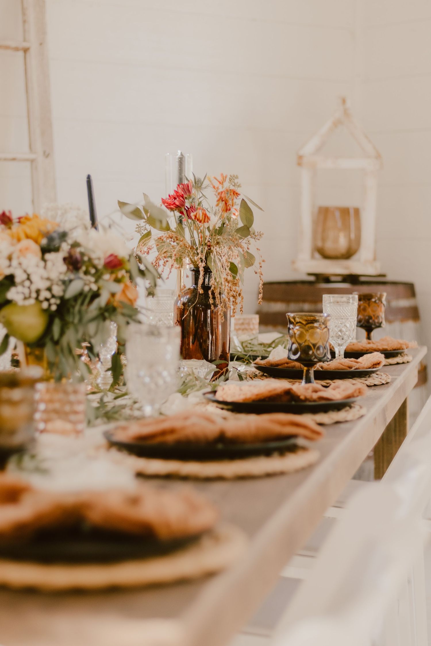 Rustic wedding table setting with autumn floral centerpieces and place settings in warm tones.