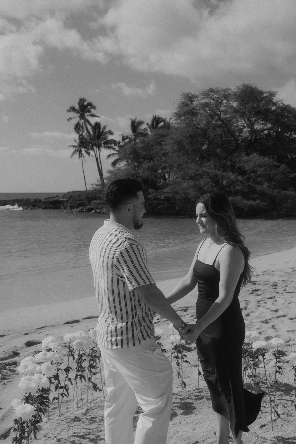A scenic beach scene unfolds with palm trees and ocean views as a couple shares a special moment on the sand.