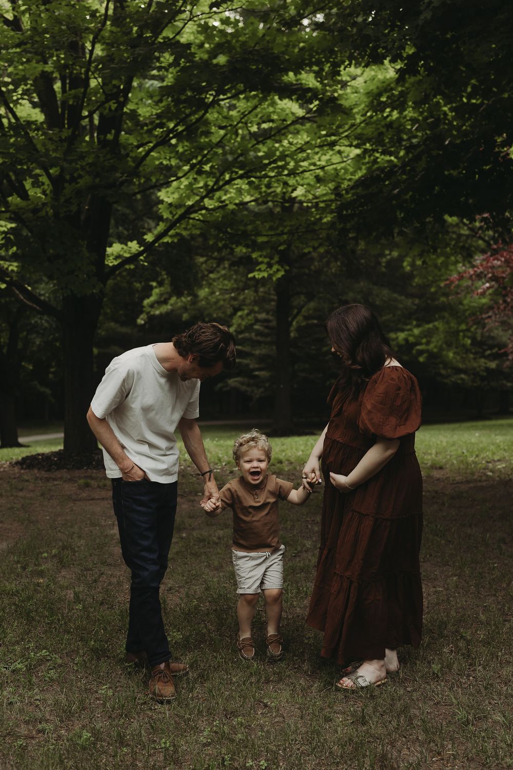 People enjoy a playful moment together in a lush green forest setting during a photo session.