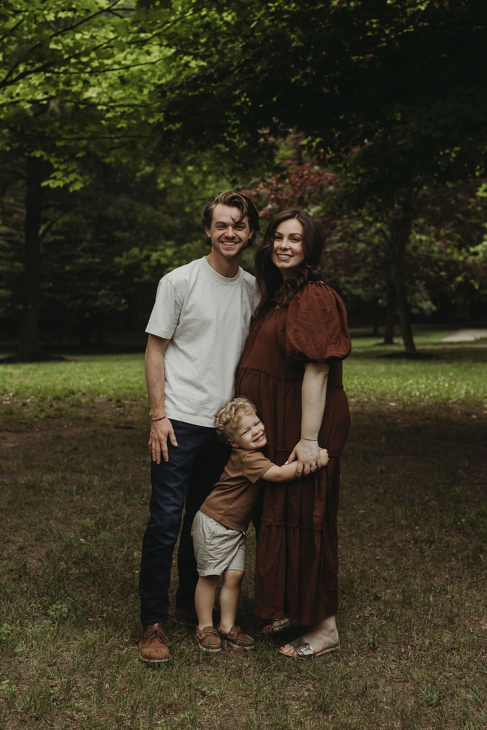 A family photo series captures candid moments of togetherness in a wooded outdoor setting.