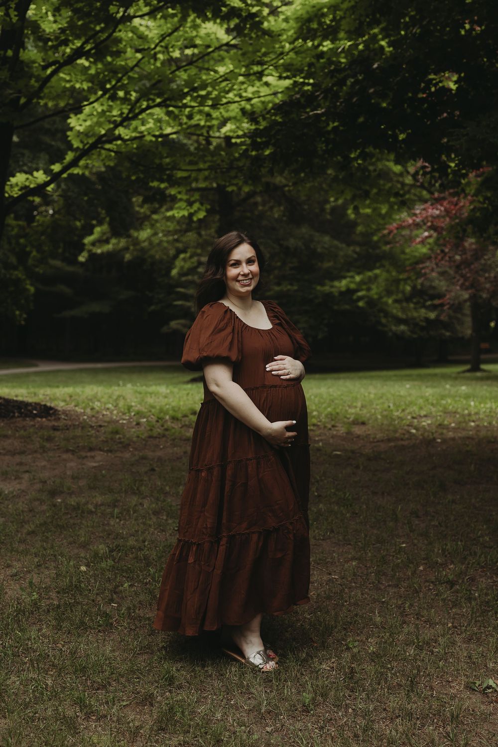 A figure in a flowing brown dress poses joyfully against a lush green outdoor backdrop in a series of photo shots.