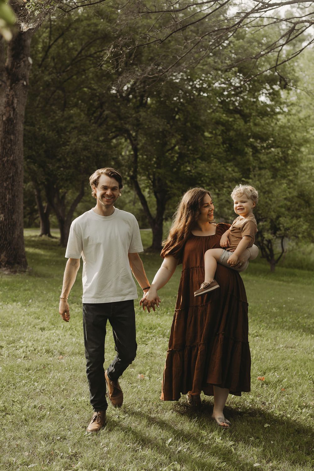 Family enjoying quality time together while walking in a lush green park on a sunny afternoon.