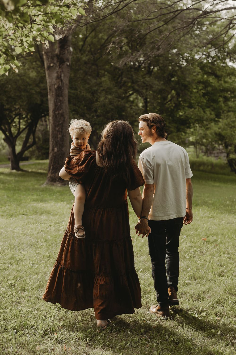 Four people walking together through a sunlit grassy field on a summer afternoon.