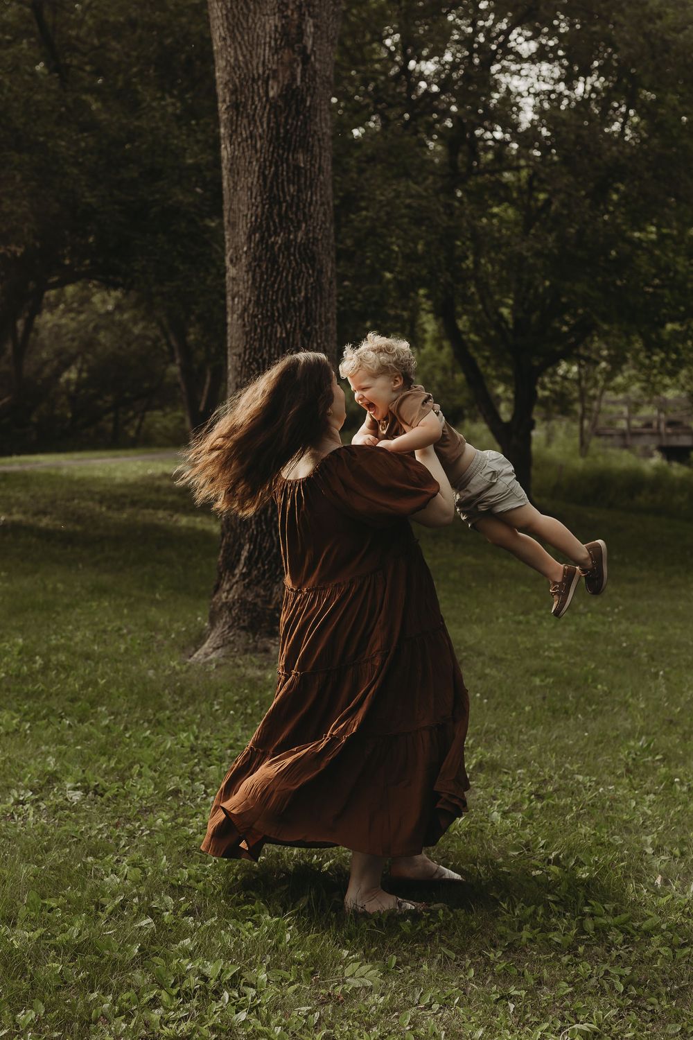A series of artistic photos showing someone in a brown dress twirling and dancing in a grassy outdoor setting at dusk.