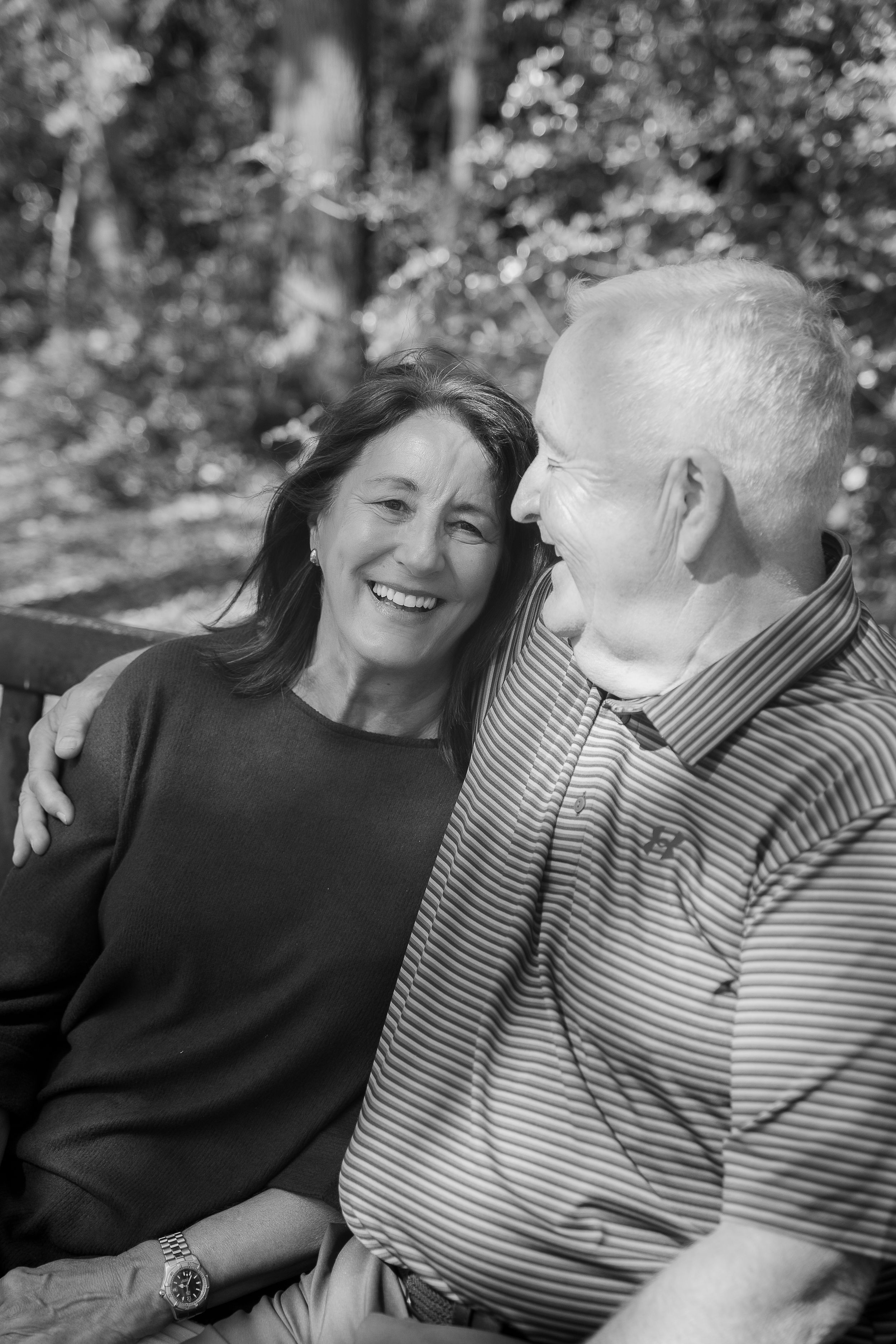 Black and white series of candid moments showing a couple in casual attire sharing joyful laughter outdoors.
