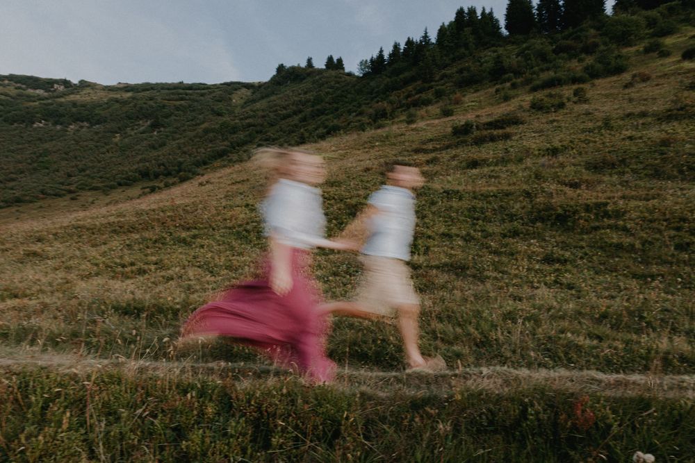 Motion-blurred figures moving through a mountainous landscape at dusk.
