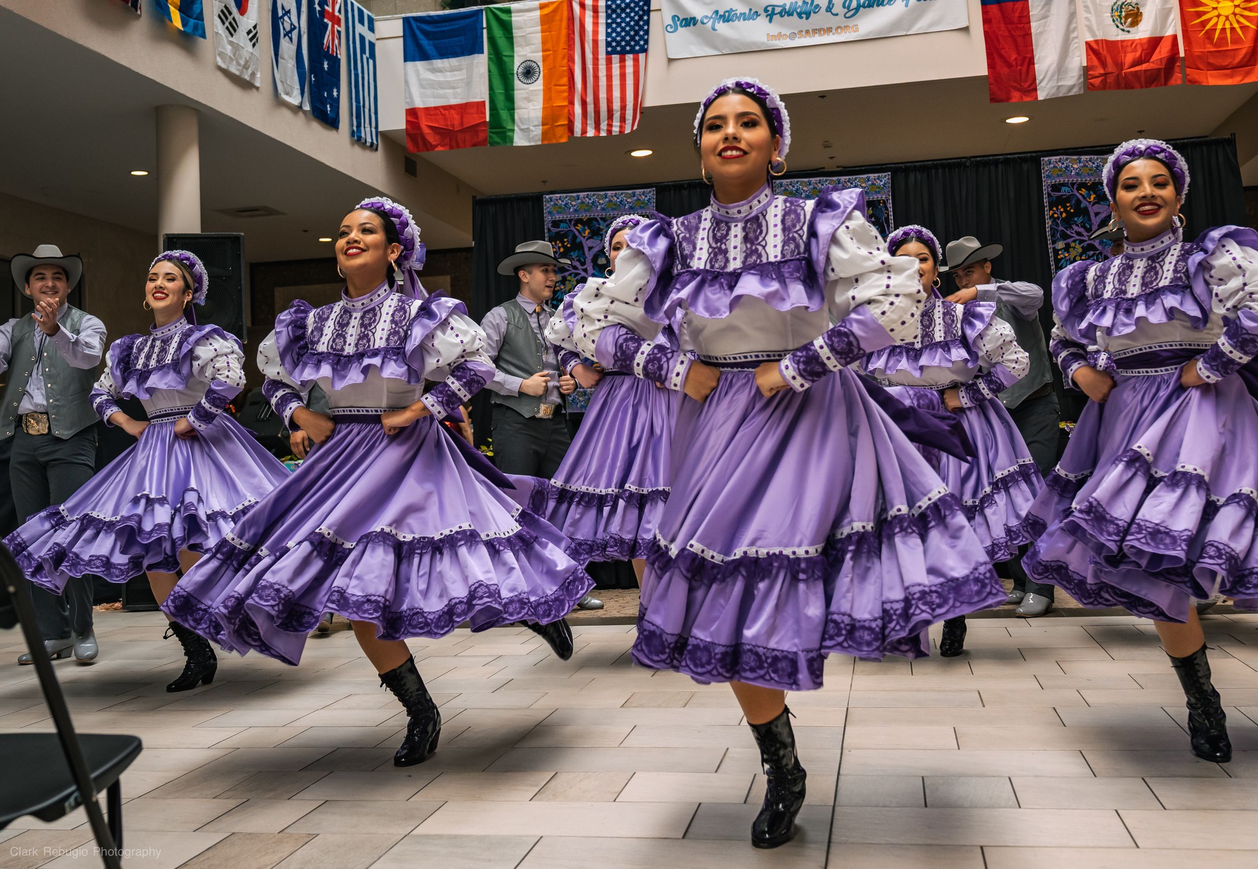 Female folkloric dancers twirling their purple skirts during a traditional Mexican dance performance at a community celebration.
