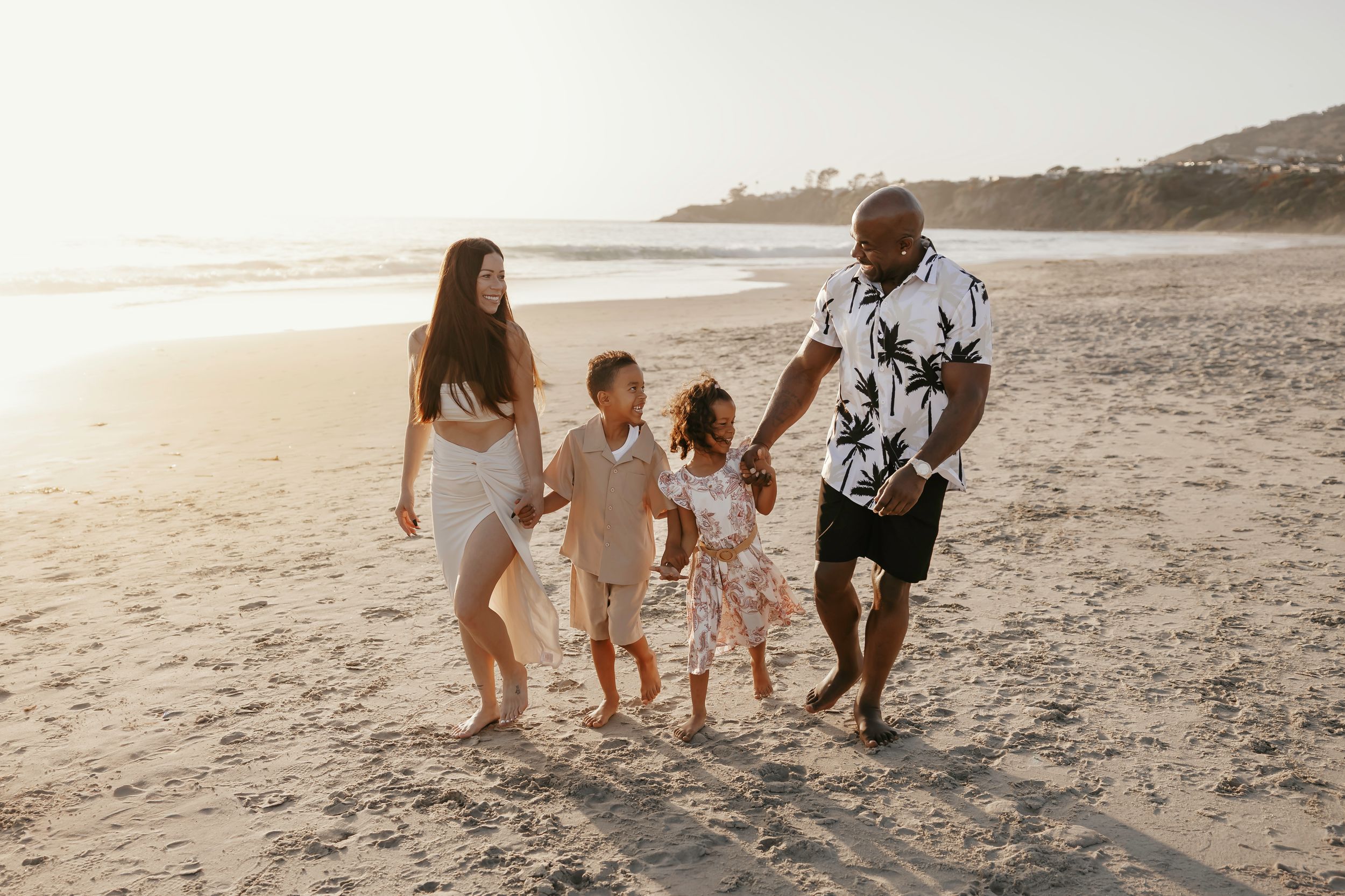 A group enjoys a sunset photoshoot on the beach near Huntington Beach Pier with golden light illuminating the sand.