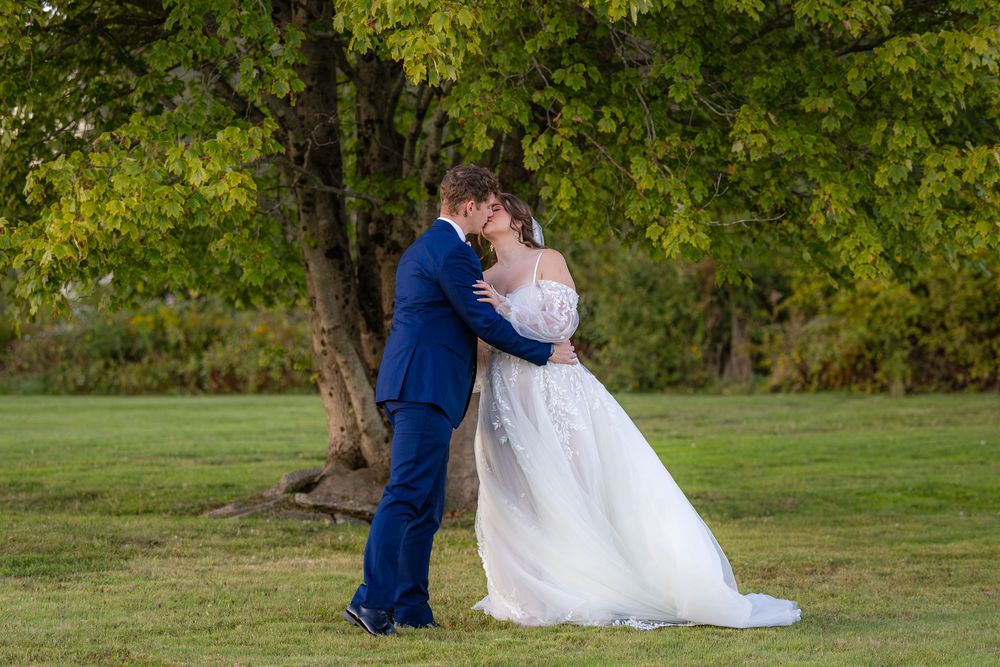 A couple in wedding attire shares tender moments during an outdoor photo session in a lush green park setting.
