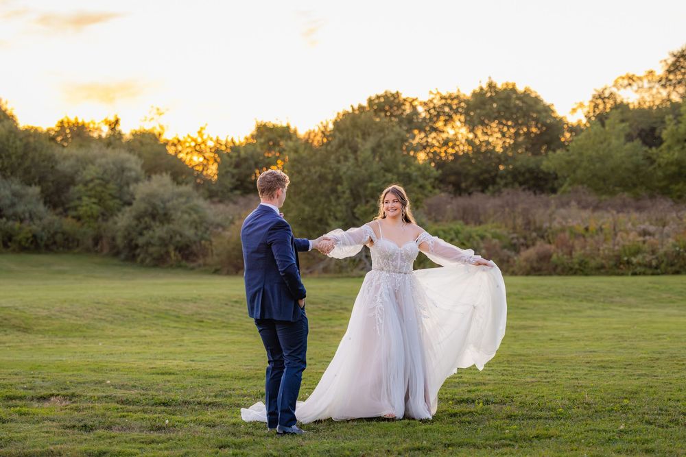 Couple dancing together in a lush green field during a sunset wedding photo session.